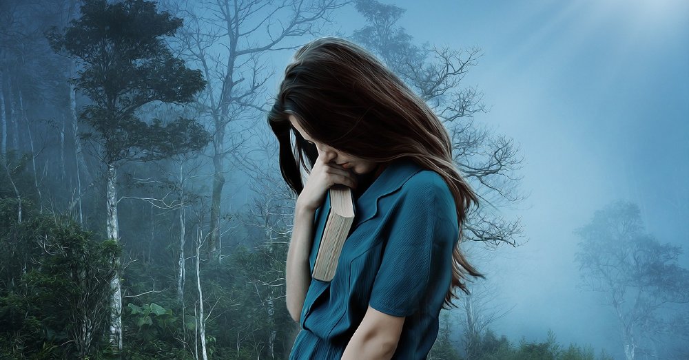 Traurige Frau mit Buch im Wald